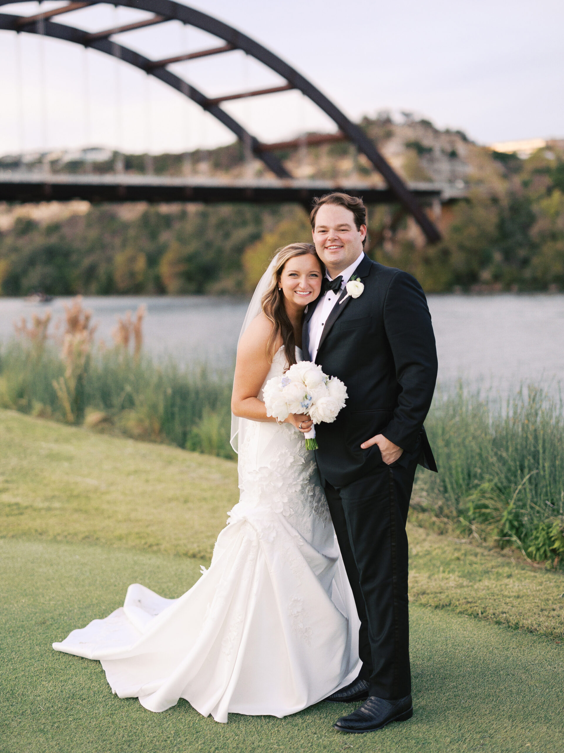 Bride and groom posing by a serene lake on their wedding day, coordinated by Olive & Eden Weddings