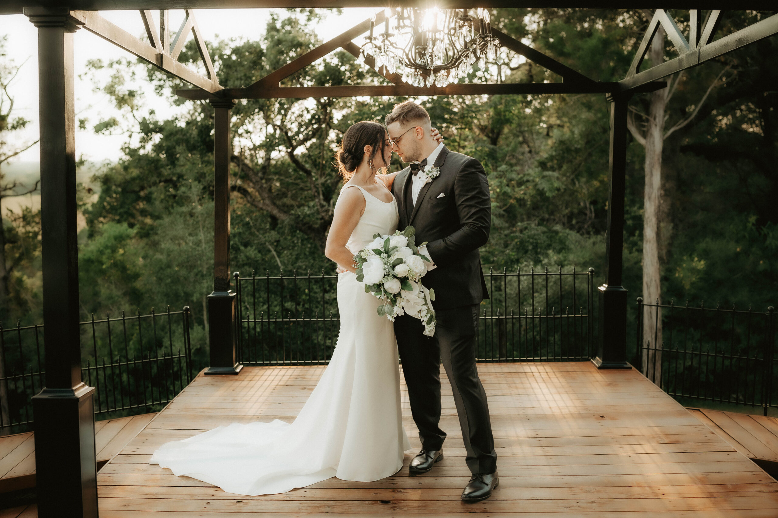Bride and groom share a romantic moment under an elegant gazebo by Olive & Eden, a testament to flawless wedding planning and design.