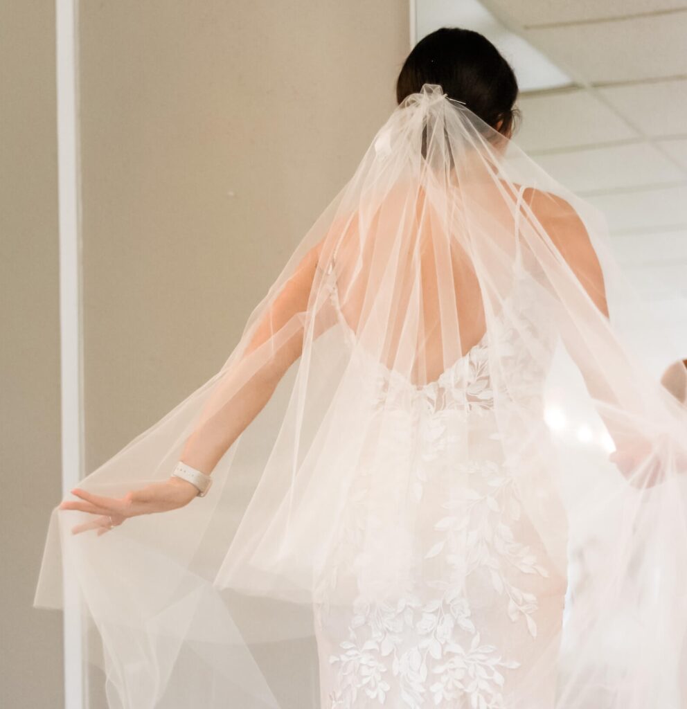 Bride adjusting elegant lace wedding veil in Austin bridal boutique during stress-free dress fitting with Olive & Eden Weddings