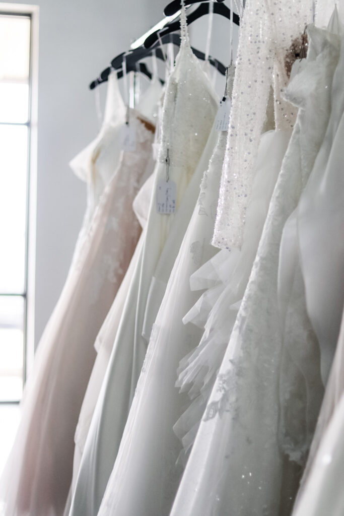 Collection of elegant wedding dresses hanging in Austin bridal boutique for luxury dress shopping with Olive & Eden Weddings