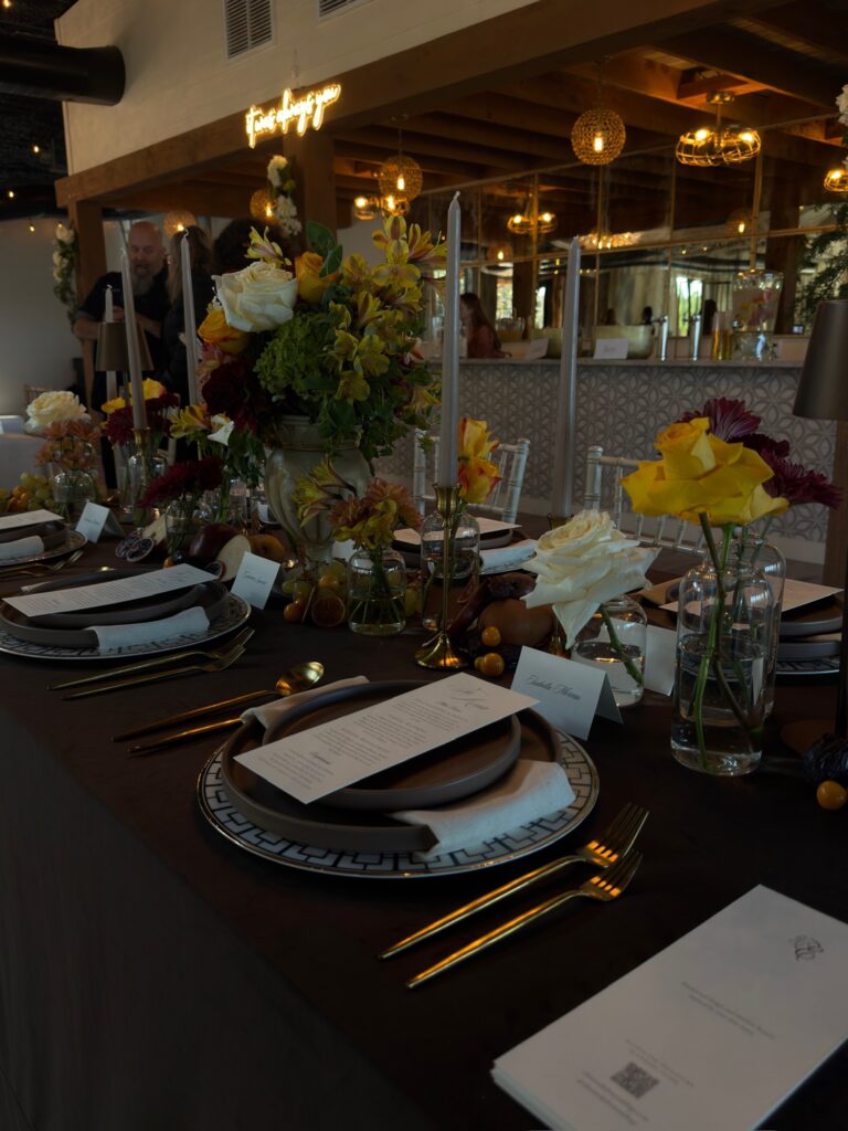 Full view of a luxury moody wedding reception table featuring chocolate brown velvet linens, gold flatware, and romantic taper candles designed by Austin wedding planner Olive & Eden.