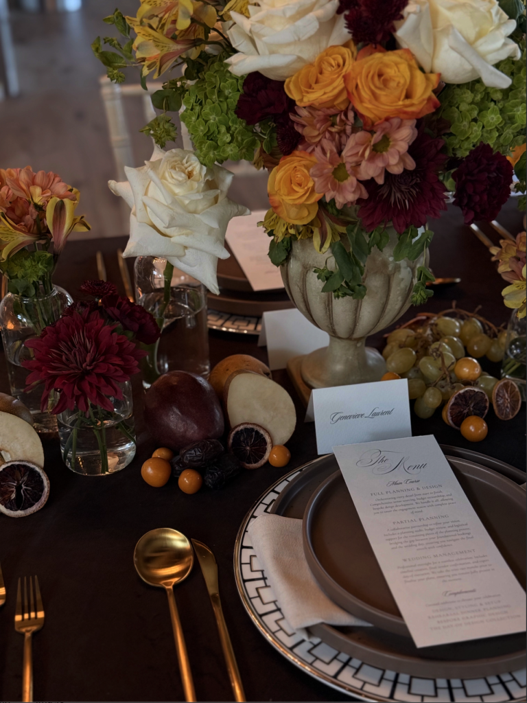 Vertical detail shot of vintage floral urn, dried citrus, fresh fruit accents, and bespoke wedding menu card designed by Austin wedding planner Olive & Eden.