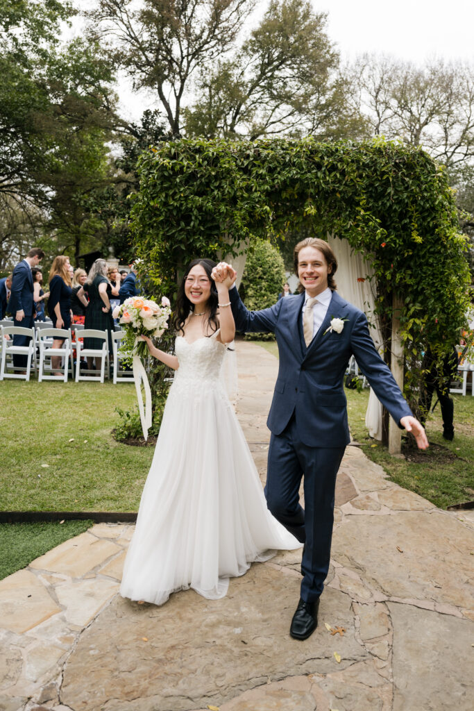 Joyful bride and groom recessional at a lush Austin garden wedding, orchestrated by full-service wedding planner Olive & Eden.