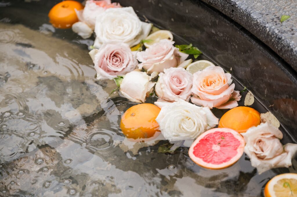 Close-up of floating roses and citrus slices in a stone fountain, showcasing artistic wedding design textures.