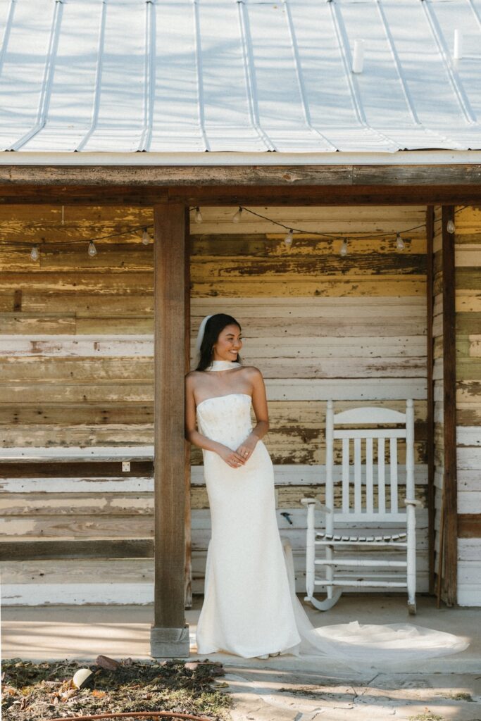 A modern bride standing on the porch of a historic wood cabin at Hill Country Wedding Chapel in Fredericksburg.