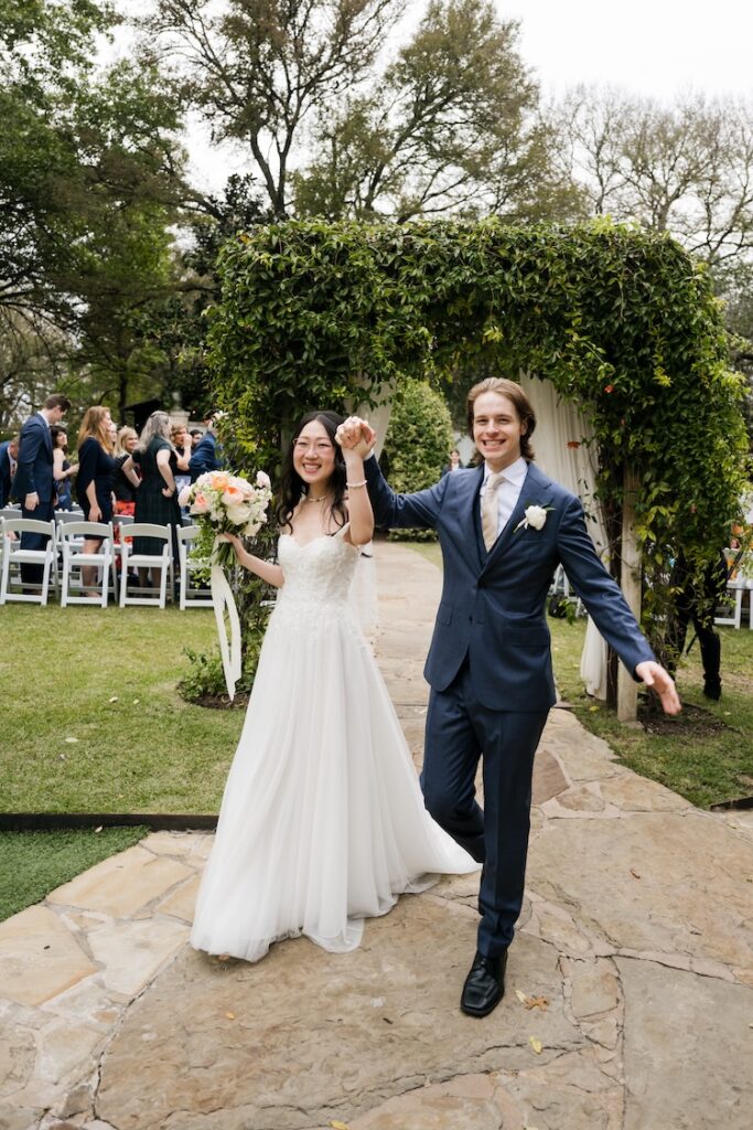 A joyful bride and groom laughing during their "just married" walk through the gardens at a Hummingbird House wedding.