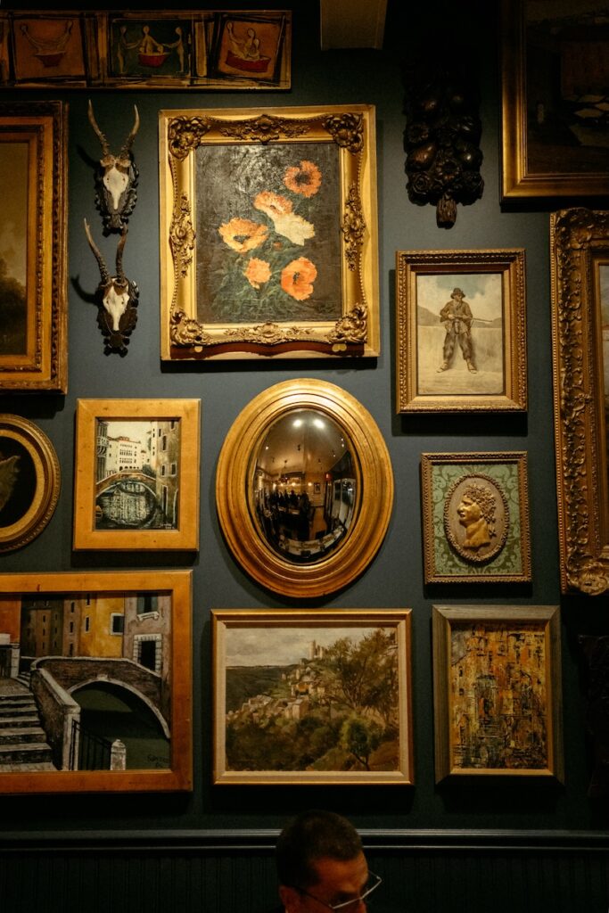 A curated gallery wall of vintage gold frames on a stone wall at a luxury Hill Country wedding.