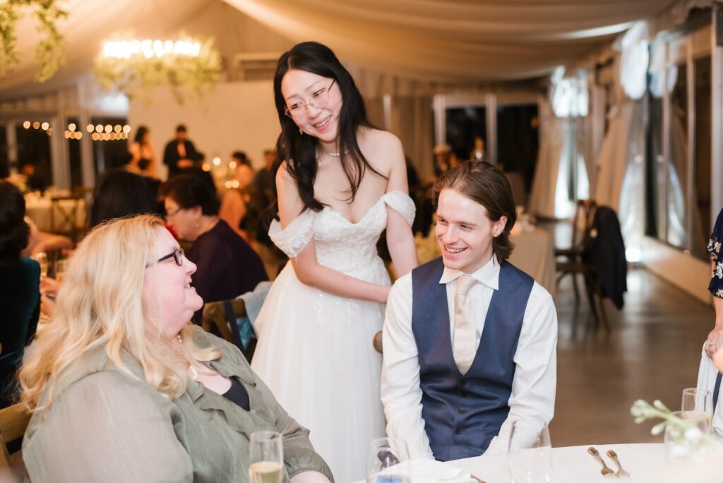 A bride and groom visiting guest tables during dinner, a moment protected by the timeline stewardship of Olive & Eden.